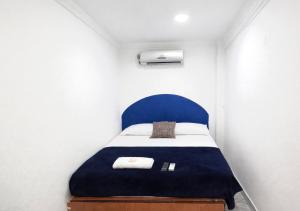 a small bedroom with a bed with a blue headboard at Ocean Blue Centro Histórico Hotel in Santa Marta