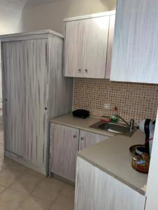 a kitchen with white cabinets and a sink at Sea and Stone Apartment in Afitos