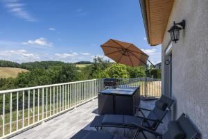 a patio with a table and chairs and an umbrella at Maison Chalet in Le Nayrac