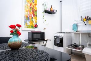 a vase with red roses sitting on a table in a kitchen at Cozy West Coast Studio in Cabo Rojo