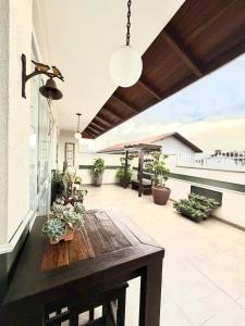 a patio with a wooden table and potted plants at Quarto 2P Joinville Costa e Silva perto Centro in Joinville