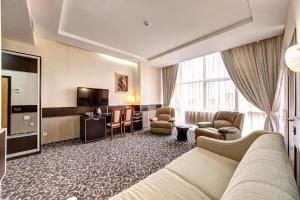 a hotel room with a couch and chairs and a television at Terra Nova Spa Hotel in Hatne