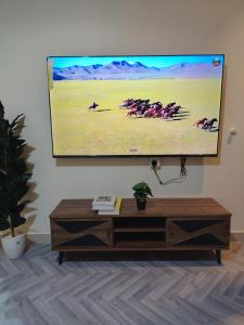 a flat screen tv hanging on a wall in a living room at Sukoon Apartment شقة سكون 2 in Buraydah