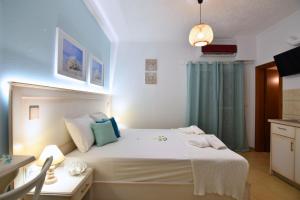 a bedroom with a large white bed and a desk at El Greco Nei Pori in Nei Poroi
