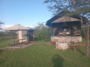 a tent with a table and chairs and an umbrella at Turacova Safaris & Accommodation in Mara Simba
