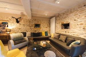 a living room with couches and a stone wall at Les Tilleuls de Marie in Saint-Edmond