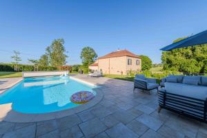 a swimming pool in a yard with two chairs at Les Tilleuls de Marie in Saint-Edmond