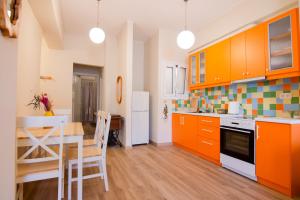 a kitchen with orange cabinets and a table and chairs at MC4 Residences in Loutraki