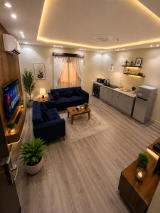 a living room with a blue couch and a kitchen at ليالي أكنان للشقق المخدومة فرع2 in Abha