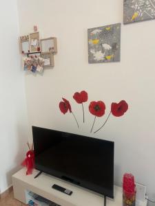 a flat screen tv in a living room with flowers on the wall at NORA House in Savona