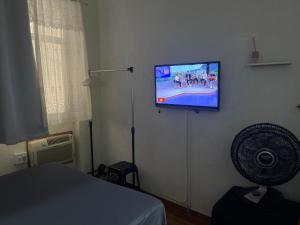 a room with a tv on a wall with a fan at Loft aconchegante - Centro Niterói in Niterói