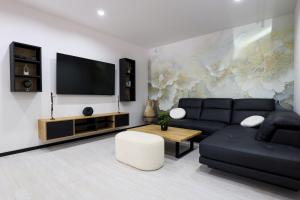 a living room with a black couch and a tv at Villa Truman Klek in Klek