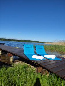 two blue chairs sitting on a dock next to the water at Wigierska Piertówka 2 in Suwałki