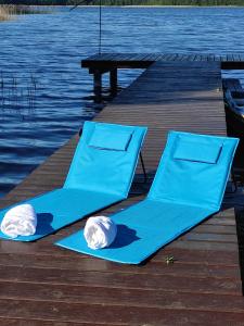 two blue chairs on a dock next to the water at Wigierska Piertówka 2 in Suwałki