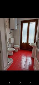 ein Badezimmer mit zwei Toiletten und rotem Fliesenboden in der Unterkunft CasaColdai in Alleghe + 14 Fotos