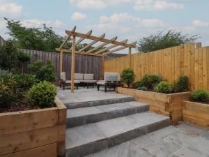 a garden with a wooden pergola and stairs at Shepherd's Lodge in Skipton