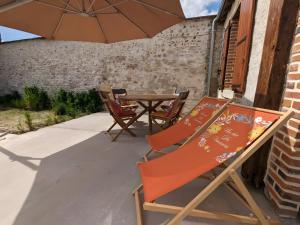 a patio with a table and chairs and an umbrella at Gîte L'air De Vacances in Bonnée