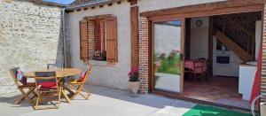 a patio with a table and chairs and a kitchen at Gîte L'air De Vacances in Bonnée