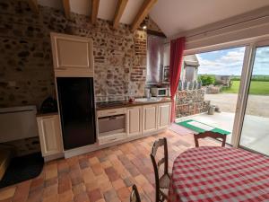 a kitchen with white cabinets and a table and a window at Gîte L'air De Vacances in Bonnée