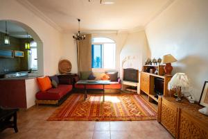 a living room with a red couch and a tv at Get Salty Guesthouse in Tamraght Ouzdar