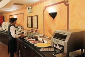 a woman standing in a kitchen preparing food at Hotel Leonardo da Vinci in Santiago
