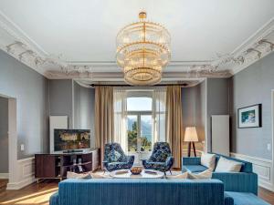 a living room with blue furniture and a chandelier at Fairmont Le Montreux Palace in Montreux