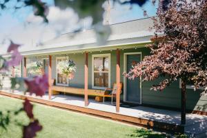 a green house with a bench on the porch at Pinedale Cozy Cabins in Pinedale