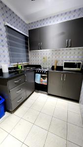 a kitchen with black cabinets and a white tile floor at Executive Deluxe Studio Apt-Osu in Christiansborg
