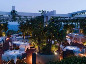 an outdoor restaurant with white tables and trees at night at Swissôtel Resort Bodrum Beach in Turgutreis +183 photos