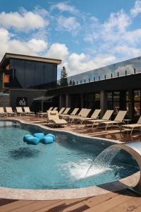 a swimming pool with lounge chairs and a building at VILSON hotel in Bukovel