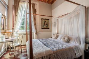 a bedroom with a canopy bed and a table and a desk at Villa Mon Paradis in Lucca