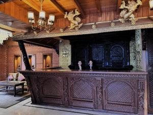 a large wooden bar with two people sitting at it at Hotel Dachi Kathmandu - Bhaktapur in Bhaktapur