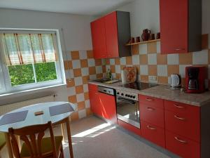 a kitchen with red cabinets and a table in it at FeWo Fink in Regen