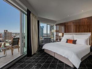 a bedroom with a large bed and a large window at Swissotel Sydney in Sydney
