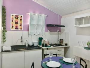 a kitchen with purple walls and a table with chairs at Casa Antiga Reformada Centro de Matão in Matão