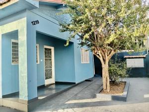 a blue building with a tree in front of it at Casa Antiga Reformada Centro de Matão in Matão