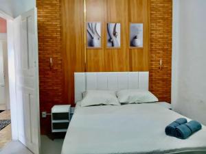 a bedroom with a white bed with two blue pillows at Casa Antiga Reformada Centro de Matão in Matão