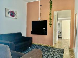 a living room with a blue couch and a tv at Casa Antiga Reformada Centro de Matão in Matão