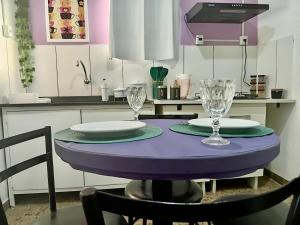 a purple table with two plates and glasses on it at Casa Antiga Reformada Centro de Matão in Matão +11 photos