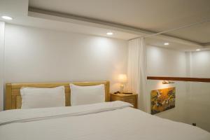 a bed with white sheets and pillows in a room at Dốc Phố Home - Dalat Homestay in Xuan An