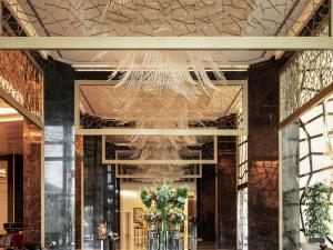 a chandelier in a lobby with flowers in vases at Raffles Istanbul in Istanbul