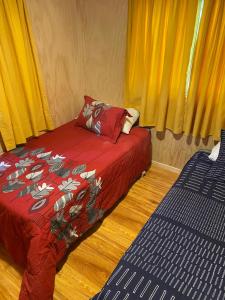 a bedroom with a red bed and yellow curtains at Cabaña Payer in Villarrica