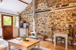 a living room with a stone wall and a table at The Wagon in Michaelstow