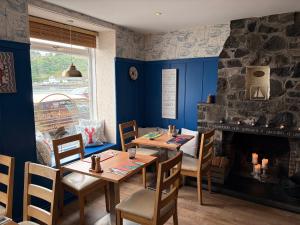 a dining room with a table and a fireplace at Mishnish Hotel in Tobermory