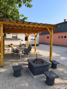 a patio with a fire pit and a wooden pavilion at Bereg Szíve Apartman in Vásárosnamény