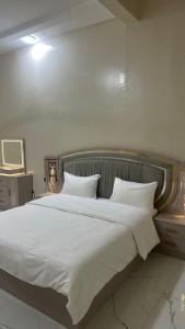 a bedroom with a large bed with white sheets and pillows at Reef Sinaw Apartments in Sinaw