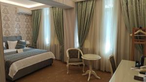 a bedroom with a bed and a table and a chair at Savoy Hotel in Chişinău +57 photos