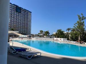 a large swimming pool with lounge chairs and a building at Piera's Paraiso Seaview in Playa Paraiso