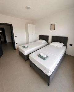 two beds in a hotel room with white walls at Apartments Lialda in Donji Štoj