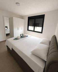 a large white bed in a bedroom with a window at Apartments Lialda in Donji Štoj